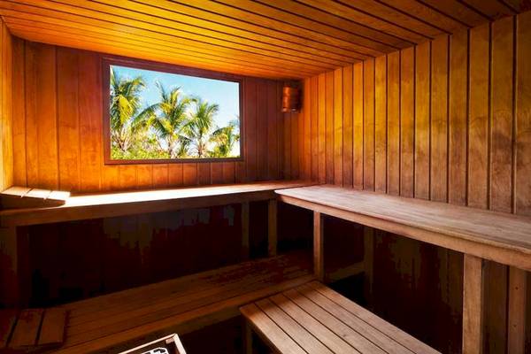 Innenansicht einer Sauna im Catalonia Royal Bavaro mit Holzwänden, Fenster und Palmen draußen.