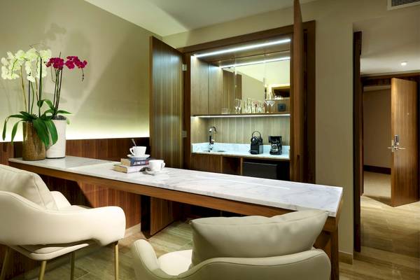 Suite-Wohnbereich im Grand Palladium Costa Mujeres Resort & Spa mit weißem Marmortisch, Sesseln und Blumenvase.