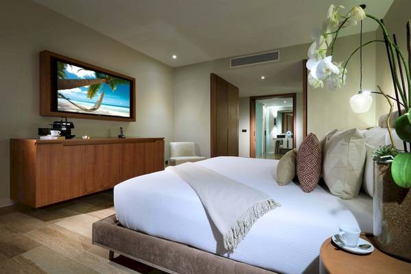 Suite-Schlafzimmer im Grand Palladium Costa Mujeres Resort mit Fernseher und Blumen.