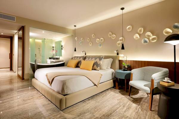 Schlafzimmer im Grand Palladium Costa Mujeres Resort mit großem Bett, Wanddekoration und Badewanne.