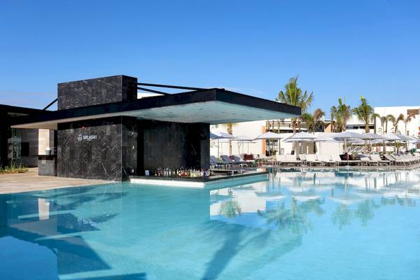 Poolbar des Grand Palladium Costa Mujeres Resort & Spa mit Lounge-Sesseln und Palmen.