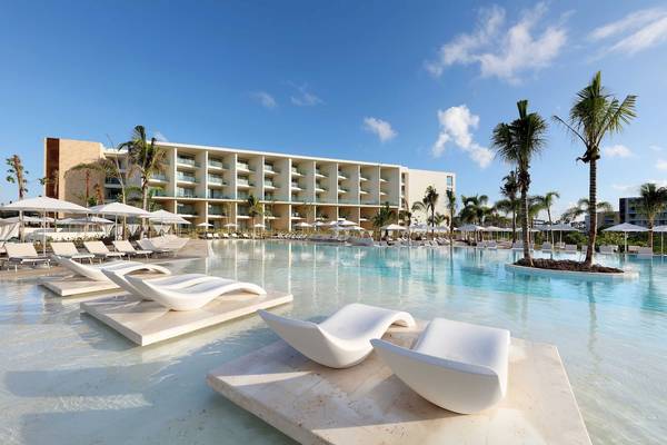 Außenpool mit weißen Sonnenliegen und Sonnenschirmen vor dem Grand Palladium Costa Mujeres Resort & Spa.