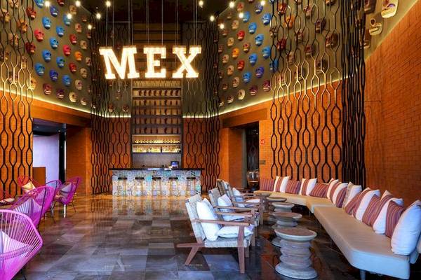 Lobby des Grand Palladium Costa Mujeres Resort & Spa mit bunten Masken an der Decke und modernen Möbeln.