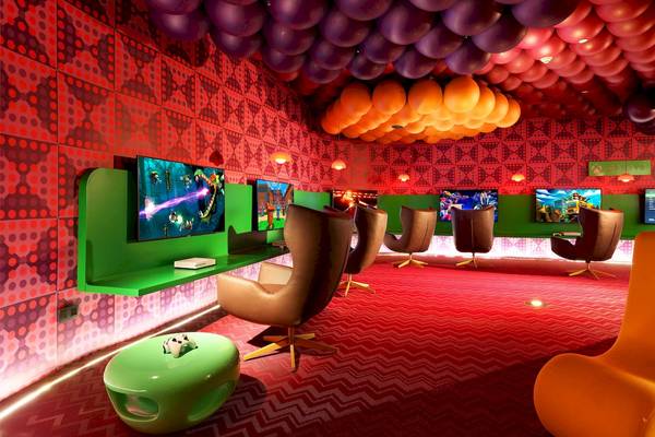 Spielzimmer im Grand Palladium Costa Mujeres Resort mit bunten Wänden, roten Teppichböden und Fernsehern.