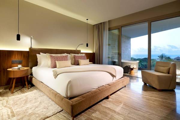 Schlafzimmer im Grand Palladium Costa Mujeres Resort mit großem Bett, Nachttischen und Meerblick.