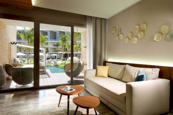 Innenraum des Grand Palladium Costa Mujeres Resort & Spa mit Wohnzimmer und Blick auf den Pool.