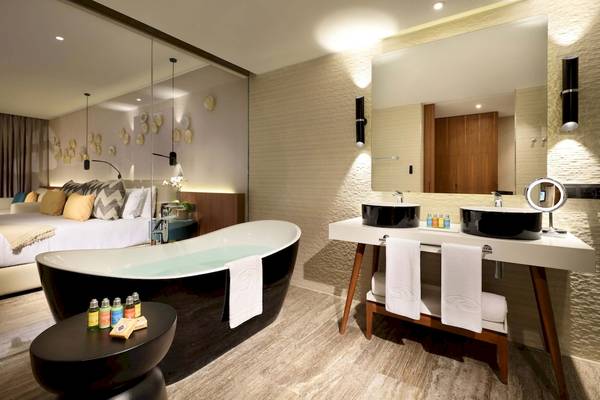 Badezimmer im Grand Palladium Costa Mujeres Resort mit Badewanne, Waschbecken und Bett im Hintergrund.