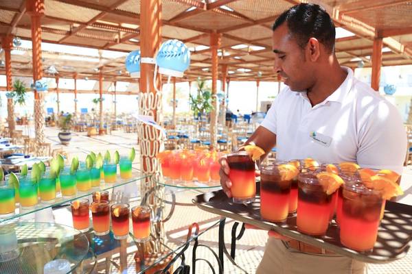 Barkeeper im LABRANDA Club Makadi Hotel serviert Cocktails auf einem Tablett.