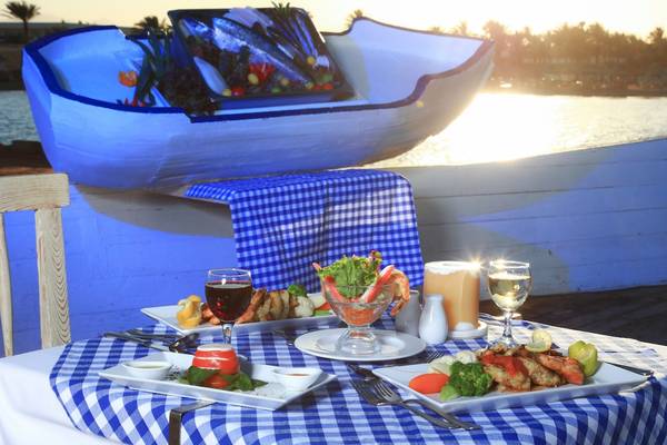 Ein Tisch im Restaurant des LABRANDA Club Makadi mit verschiedenen Gerichten und Getränken, darunter ein Fischboot im Hintergrund.