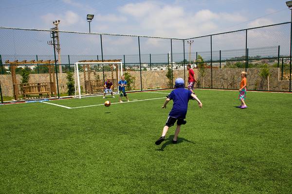 Kinder stoßen Fußball auf Rasen im Eftalia Aqua Resort Hotel