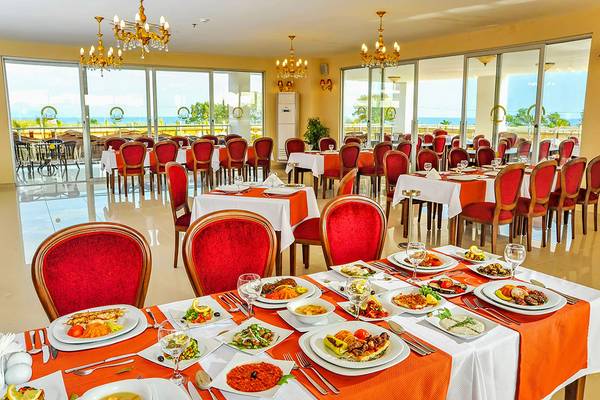 Innenansicht des Restaurants im Eftalia Aqua Resort mit vielen gedeckten Tischen und Stühlen, Meerblick durch große Fenster