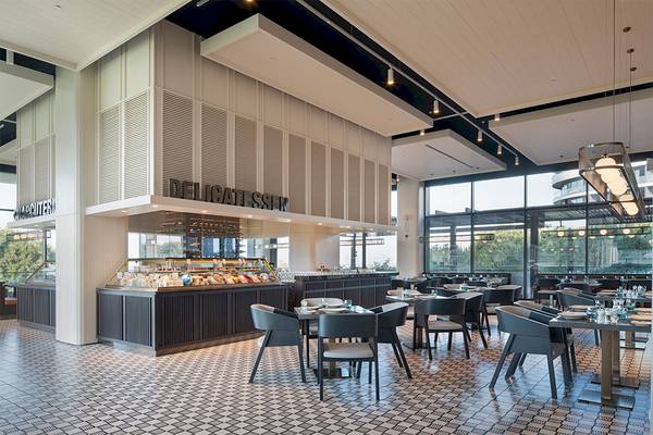 Innenansicht der Delicatessen im Voyage Belek Golf & Spa Hotel mit Tisch, Stühlen und Buffet.