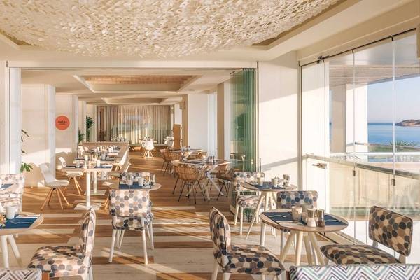 Innenansicht des Restaurants im Amare Beach Hotel Ibiza mit Tischen und Stühlen, Blick auf das Meer.