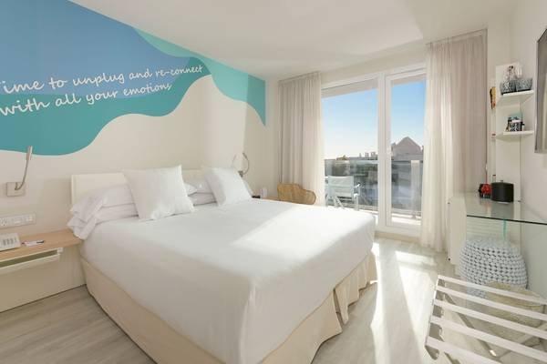 Innenansicht eines Zimmers im Amare Beach Hotel Ibiza mit Bett, Schreibtisch und Balkon