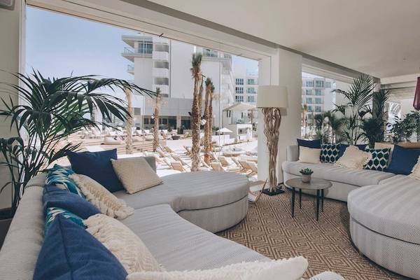 Lobby-Lounge im Amare Beach Hotel Ibiza mit großen Fenstern, Pflanzen und modernen Möbeln.