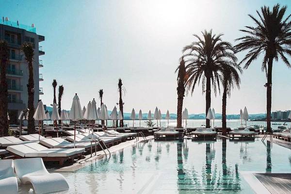 Außenpool des Amare Beach Hotel Ibiza mit Loungeliegen und Palmen