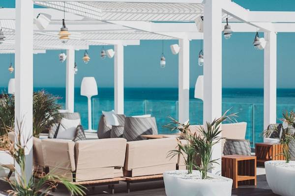 Terrasse im Amare Beach Hotel Ibiza mit Blick auf das Meer und weißen Möbeln.