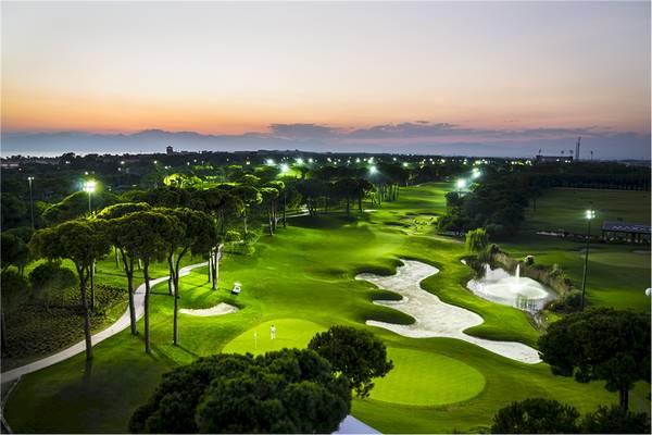 Aussicht auf den Golfplatz des Voyage Belek Golf & Spa bei Nacht mit Beleuchtung.