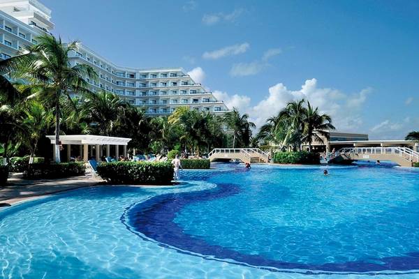 Außenansicht des Riu Caribe Hotels mit großem Swimmingpool und tropischen Palmen