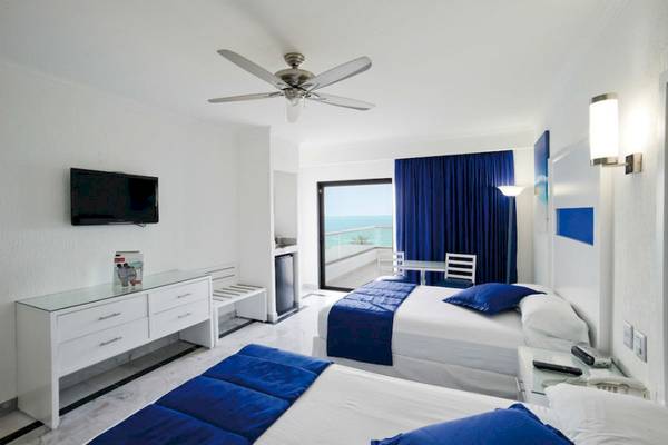 Hotelzimmer des Riu Caribe mit Blick auf das Meer, zwei Betten, Fernseher und Möbel.