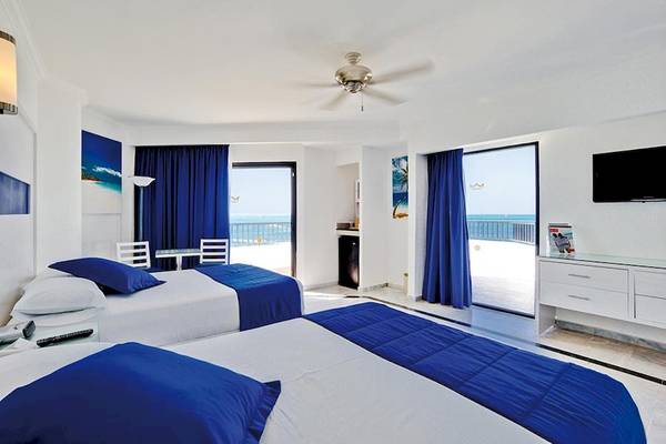 Zimmer im Riu Caribe Hotel mit Blick auf das Meer und zwei Betten mit blauen Laken.