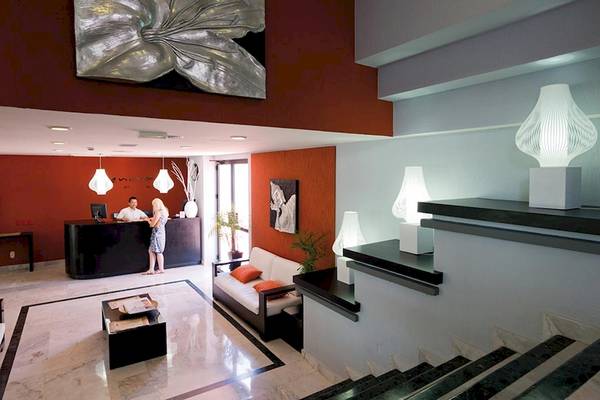 Empfangsbereich des Riu Caribe Hotels mit Rezeption, Couch und Lampen.