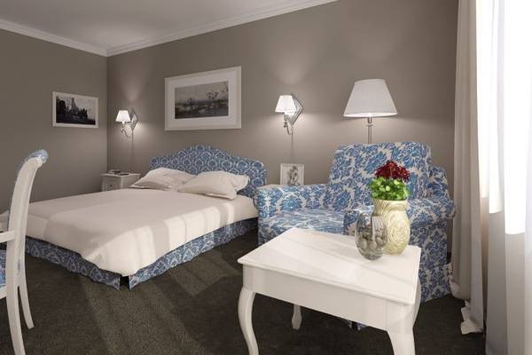 Schlafzimmer im Sofia Hotel mit Doppelbett, zwei Sesseln, Nachttischen und Lampen.