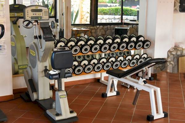 Fitnessstudio im Hotel Baia del Sole mit diversen Geräten und Hanteln.