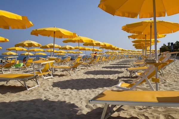 Strand des Baia del Sole Hotels mit vielen gelben Sonnenschirmen und Liegestühlen