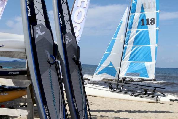 Segelboot und Surfbretter am Strand des Baia del Sole Hotels.