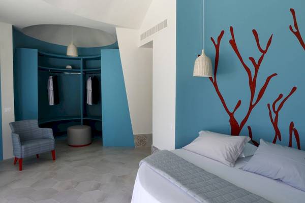 Schlafzimmer im Baia del Sole Hotel mit blauen Wänden und roten Wanddekorationen.