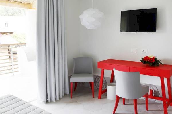 Ein Zimmer im Baia del Sole Hotel mit einem roten Schreibtisch und zwei Stühlen.