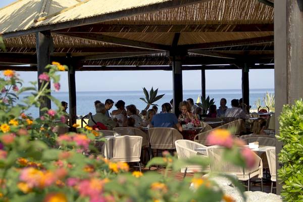 Gäste sitzen auf der Terrasse des Baia del Sole Hotels mit Blick auf das Meer.