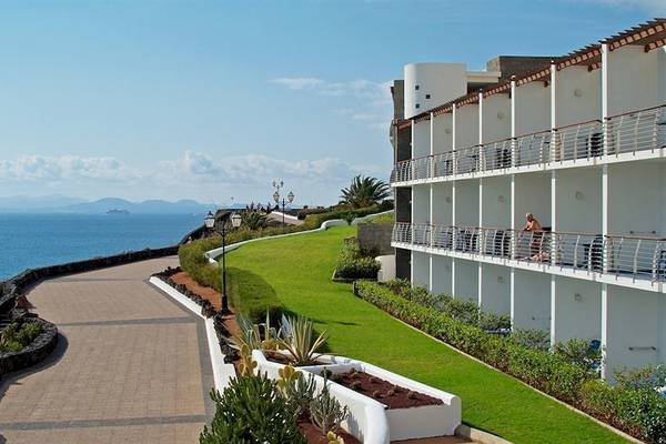 Außenansicht des Mirador Papagayo by LIVVO Hotels mit Blick auf das Meer und eine Person auf dem Balkon.