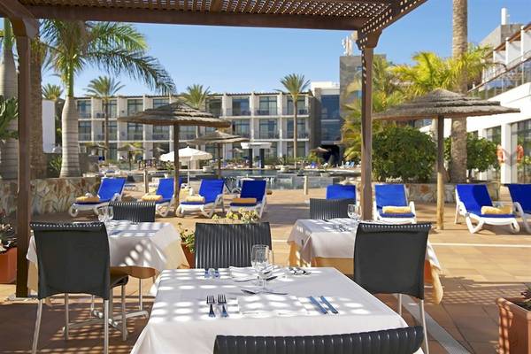 Terrasse des Mirador Papagayo by LIVVO Hotels mit Tischen und Stühlen unter Schirmen.