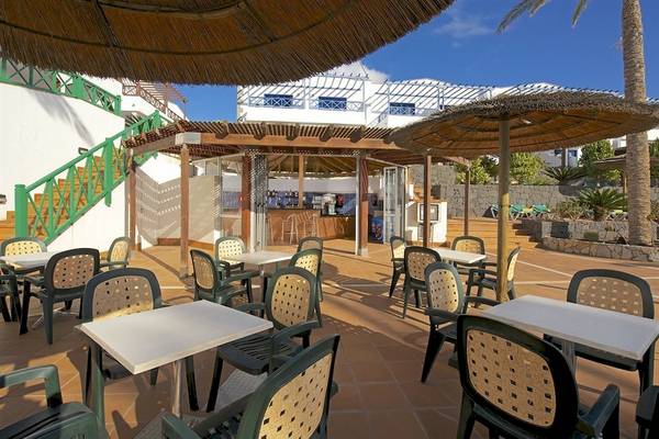 Terrasse des Mirador Papagayo by LIVVO Hotels mit Tischen und Stühlen unter Sonnenschirmen.