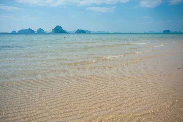 Strand des Tubkaak Krabi Boutique Resorts mit kleinen Wellen im Wasser und Inseln im Hintergrund