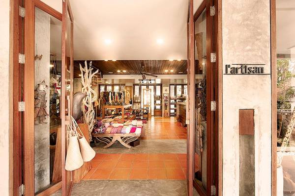 Eingangsbereich eines L'artisan Boutique-Ladens mit Holztüren und orangefarbenen Fliesen