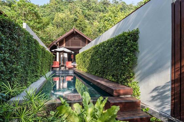 Außenbereich des Tubkaak Krabi Boutique Resorts mit Pool, Lounge-Stühlen und Sonnenschirm.