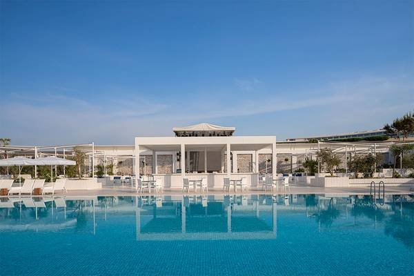 Poolbereich des Voyage Belek Golf & Spa Hotels mit weißen Sonnenliegen und Tischen.