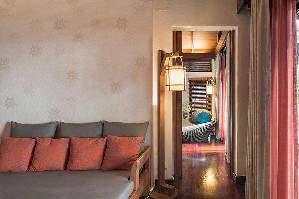 Das Innere eines Zimmers im Tubkaak Krabi Boutique Resort mit einem Bett, Kissen, Lampen und einem Flur.