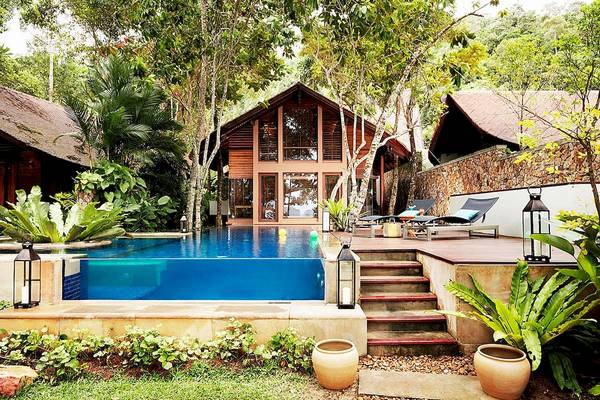 Außenansicht des Tubkaak Krabi Boutique Resorts mit Pool, Lounge-Bereich und umliegenden Pflanzen.