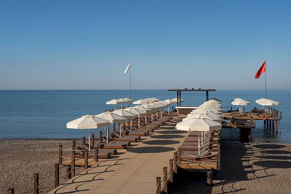 Strandlounge des Voyage Belek Golf & Spa mit Sonnenschirmen und Liegen