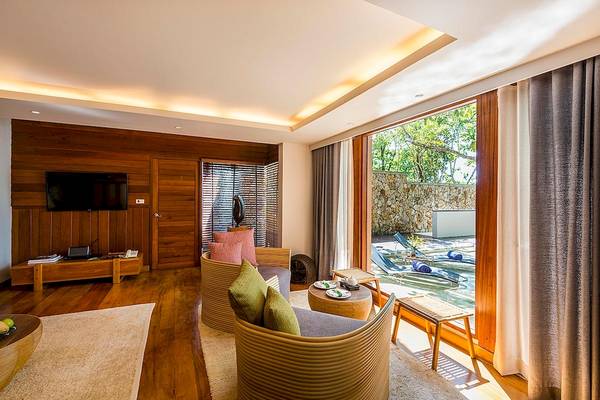 Hotel-Wohnzimmer mit Blick auf den Pool, modernes Design, Holzmöbel und große Glasfenster.