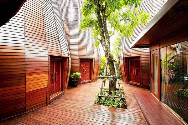 Innenhof des Tubkaak Krabi Boutique Resorts mit hölzernen Wänden und einem zentralen Baum.