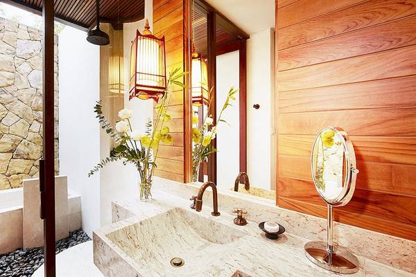 Badezimmer im Tubkaak Krabi Boutique Resort mit Marmorwaschbecken, Spiegel und Blumenvase.