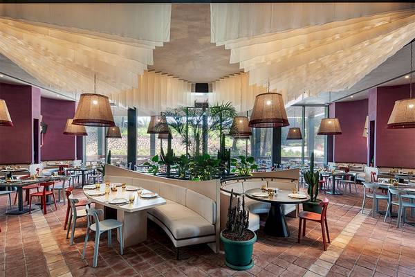 Innenansicht des Restaurants im Voyage Belek Golf & Spa Hotel mit Tischen, Stühlen und Pflanzen.
