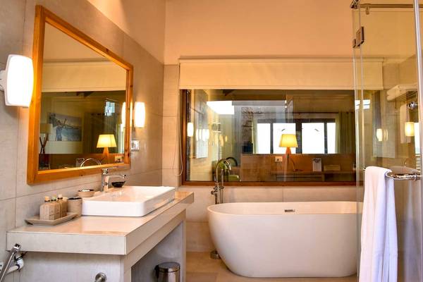 Badezimmer im Reethi Faru Resort mit Badewanne, Waschbecken und Glasdusche.