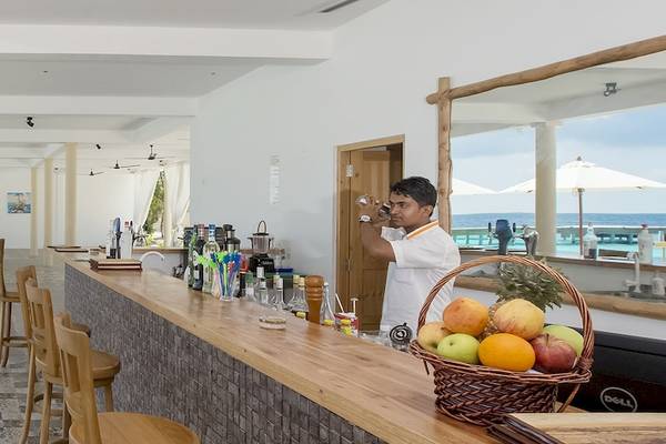 Ein Barkeeper serviert Getränke im Reethi Faru Resort mit Blick auf den Ozean.