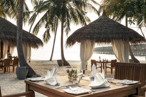 Strandrestauranttisch im Reethi Faru Resort mit Blick auf das Meer und Palmen